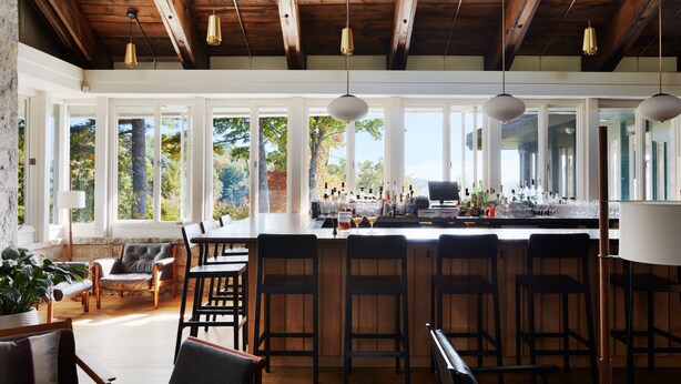A spacious bar area with high ceilings and large windows, offering views of trees and a clear sky. - The Skyline Lodge (Highlands)