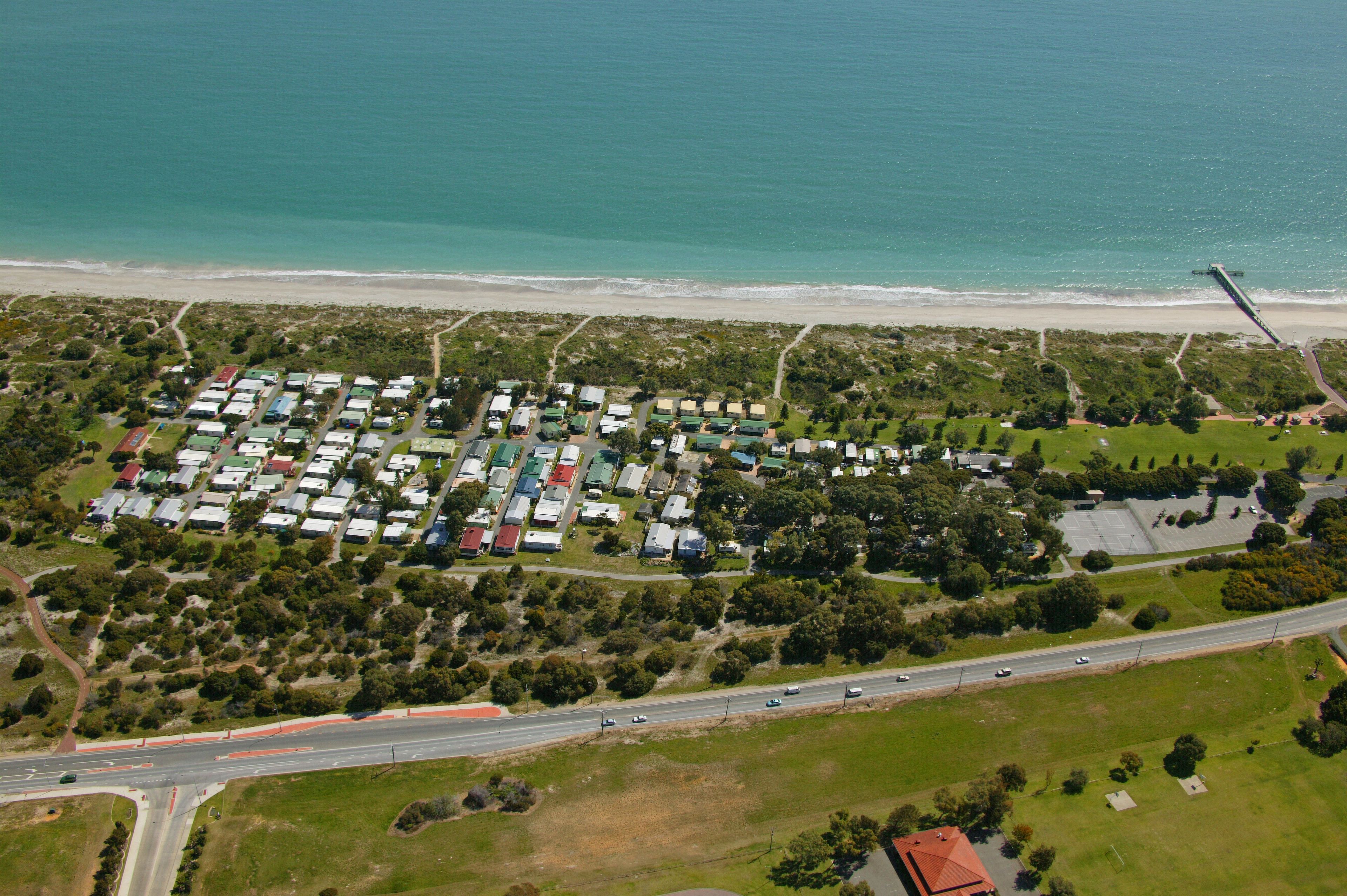 Vista aèria d'una zona residencial costanera amb diverses cases i una platja.