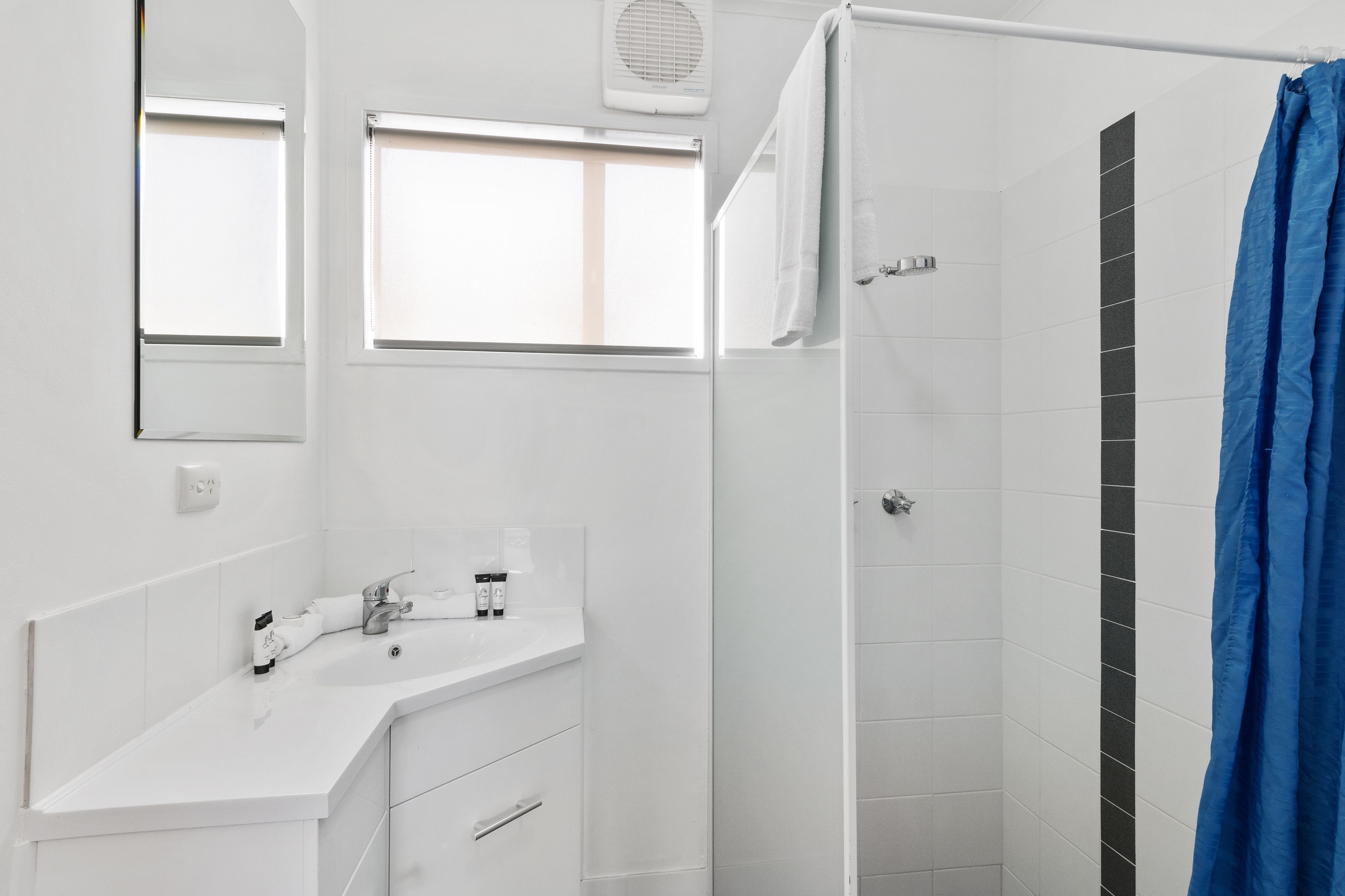 A bathroom with a white sink, mirror, and shower curtain.