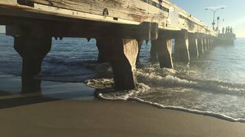 Un muelle se extiende sobre el agua, con olas rompiendo contra él.