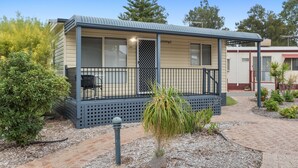 A single-story mobile home with a balcony, a small garden area, and a pathway leading to the entrance. - Discovery Parks - Coogee Beach (Coogee)