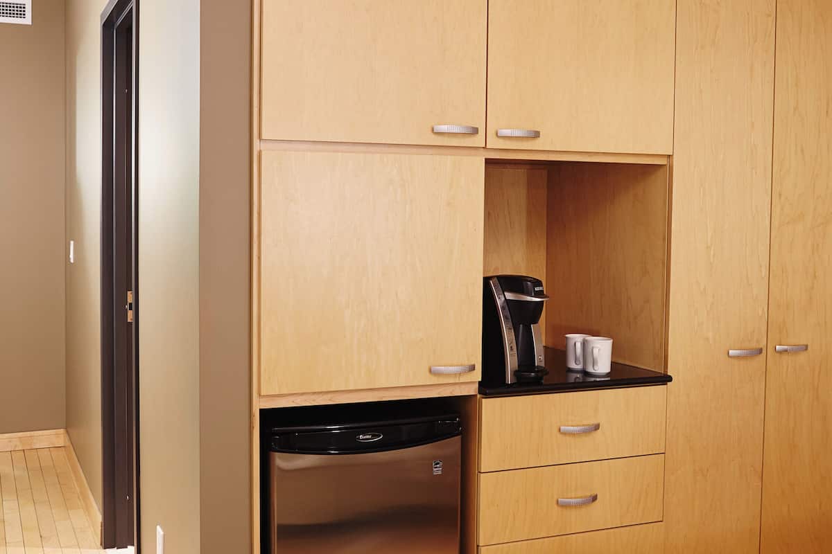 A compact kitchen with wooden cabinets, a built-in dishwasher, and a coffee maker on the countertop.