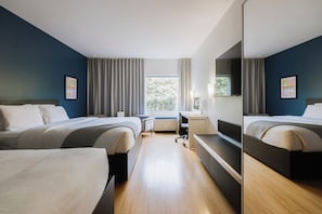 Habitación de hotel moderna con dos camas, un escritorio y un ventanal grande.