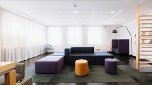 A modern living room with a sectional sofa, ottomans, a coffee table, and a magazine rack. - Hôtel Le Dauphin Saint-Hyacinthe (Saint Hyacinthe)