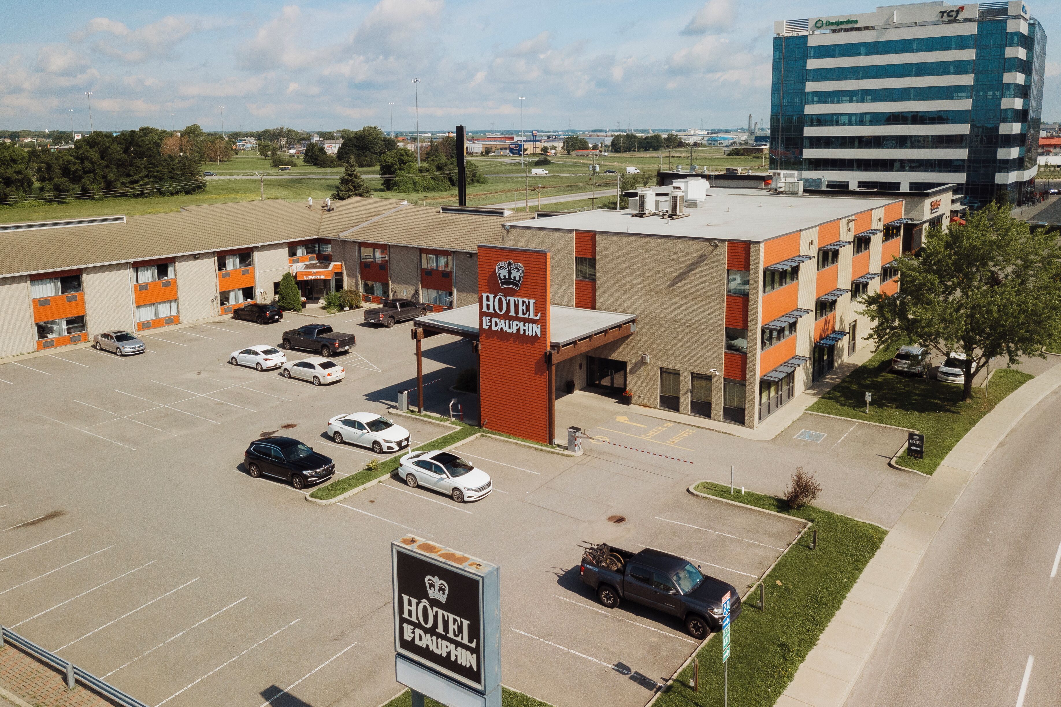 Un hotel con estacionamiento, varias edificaciones y un complejo de oficinas grande al fondo.