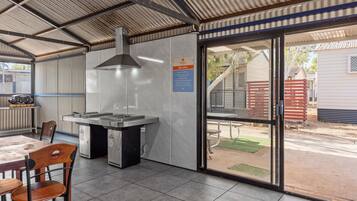Zona exterior coberta amb una zona de barbacoa, seients i vista del barri circumdant.