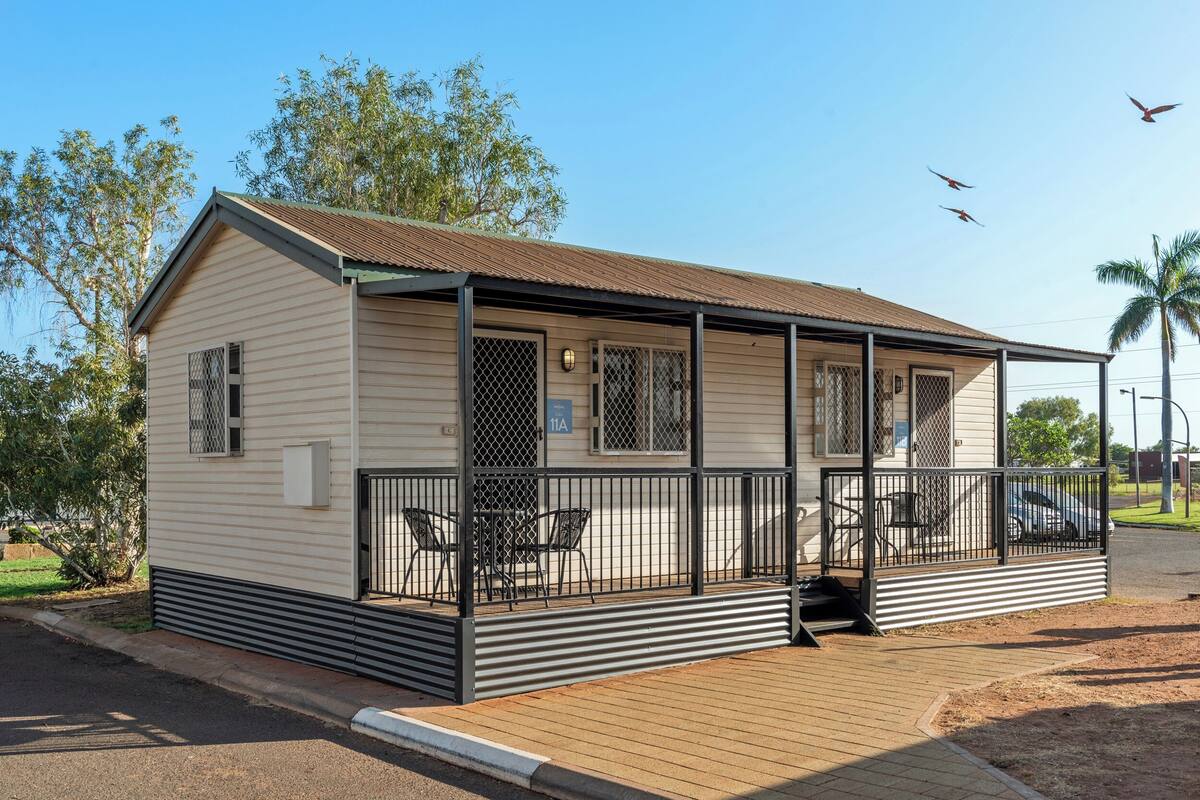 A single-story mobile home with a covered porch, a fenced patio area, and a small outdoor seating space.