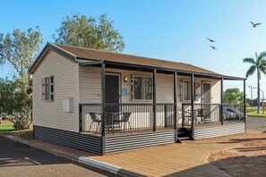 Une maison mobile de plain-pied dotée d’un porche couvert, d’un patio clos et d’un petit espace extérieur aménagé pour s’asseoir.