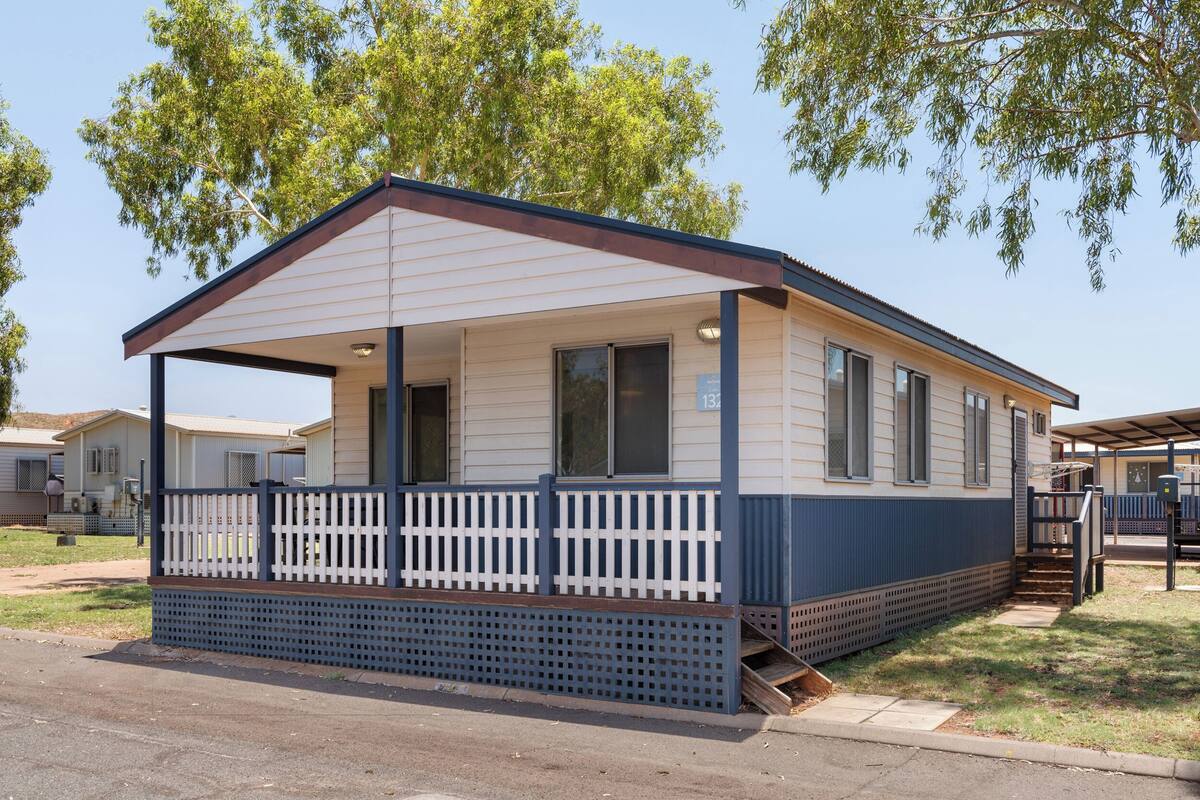 A single-story mobile home with a covered porch and a fenced front yard.