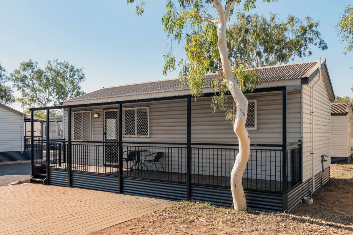 A single-story mobile home with a fenced porch, a small window, and a door.