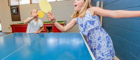 A room with a ping pong table, a red table, and a blue wall.