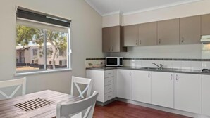 Cocina moderna con armarios blancos, microondas y ventana con vista a un barrio residencial.