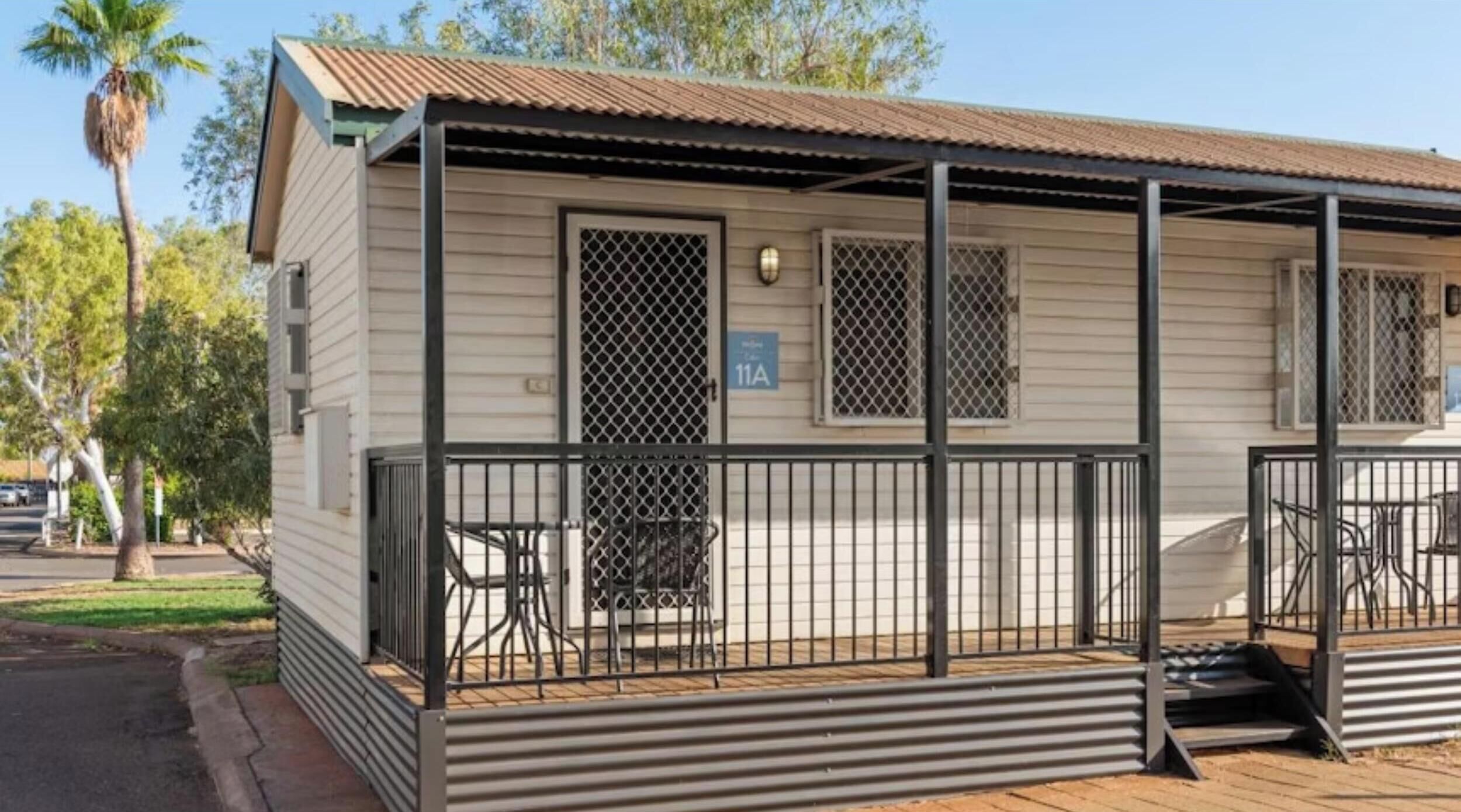 A single-story building with a covered porch, a metal railing, and a sign indicating the address.