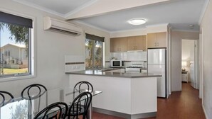 Una cocina moderna con una isla central, armarios blancos y un comedor con sillas.