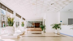 A modern hotel lobby with a spacious layout, large windows, and a reception desk. - Hotel Safari (Gandia)