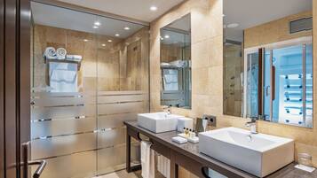 A modern bathroom with two sinks, a glass shower enclosure, and a large mirror.