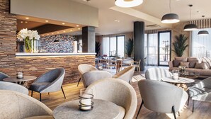 Un moderno vestíbulo de hotel con pared de piedra, zona de estar y bar.