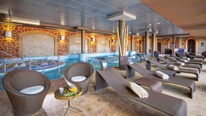 Un área de spa con piscina, sillas de descanso y una pared de piedra con diseño de mosaico.