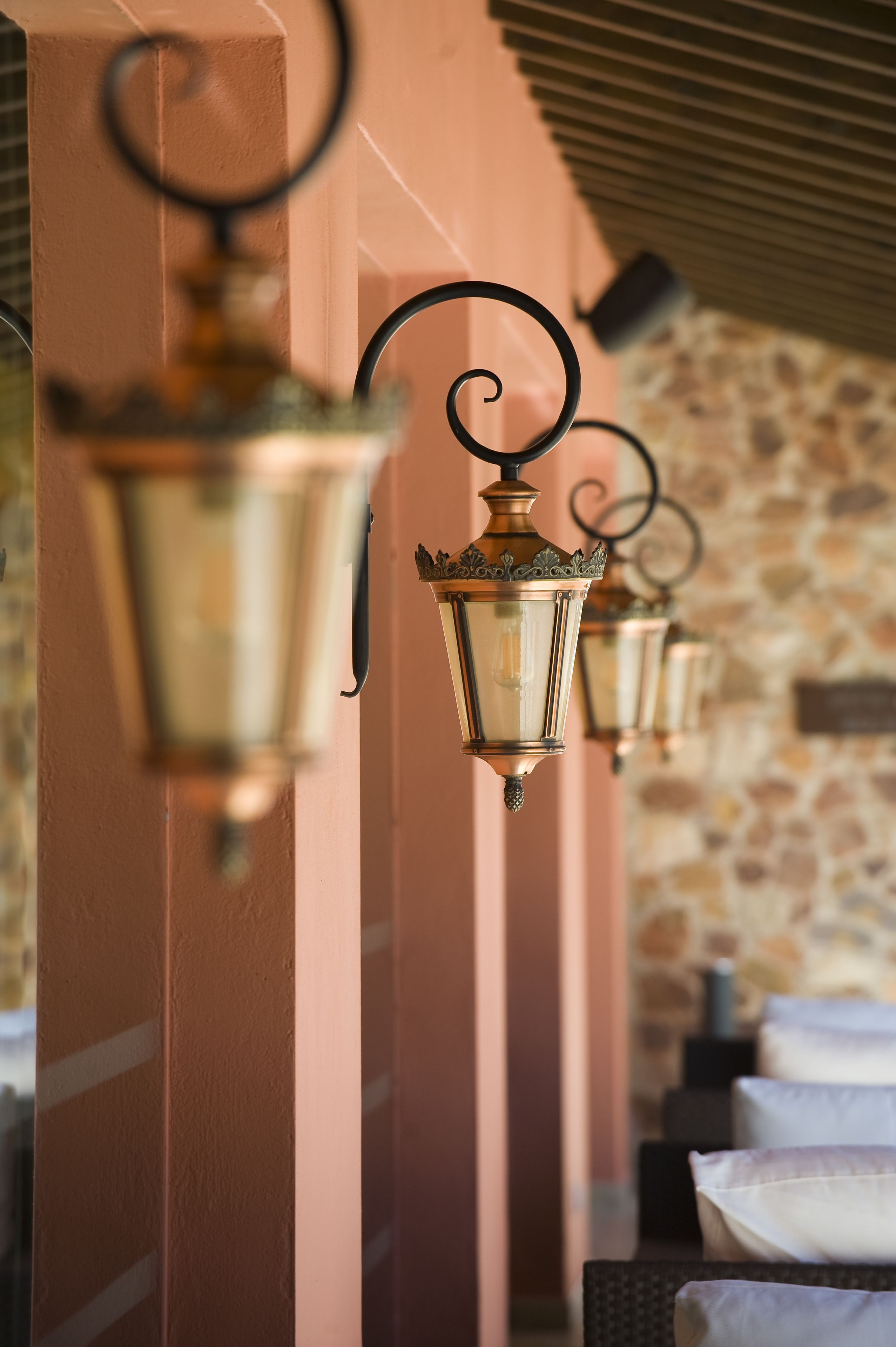 Una hilera de lámparas colgantes de estilo farol contra una pared de piedra.