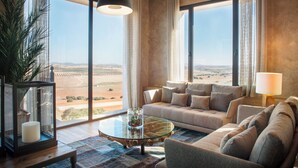 Amplia sala de estar con un sofá grande, una mesa de centro de vidrio y vistas a un paisaje desértico a través de amplias ventanas.