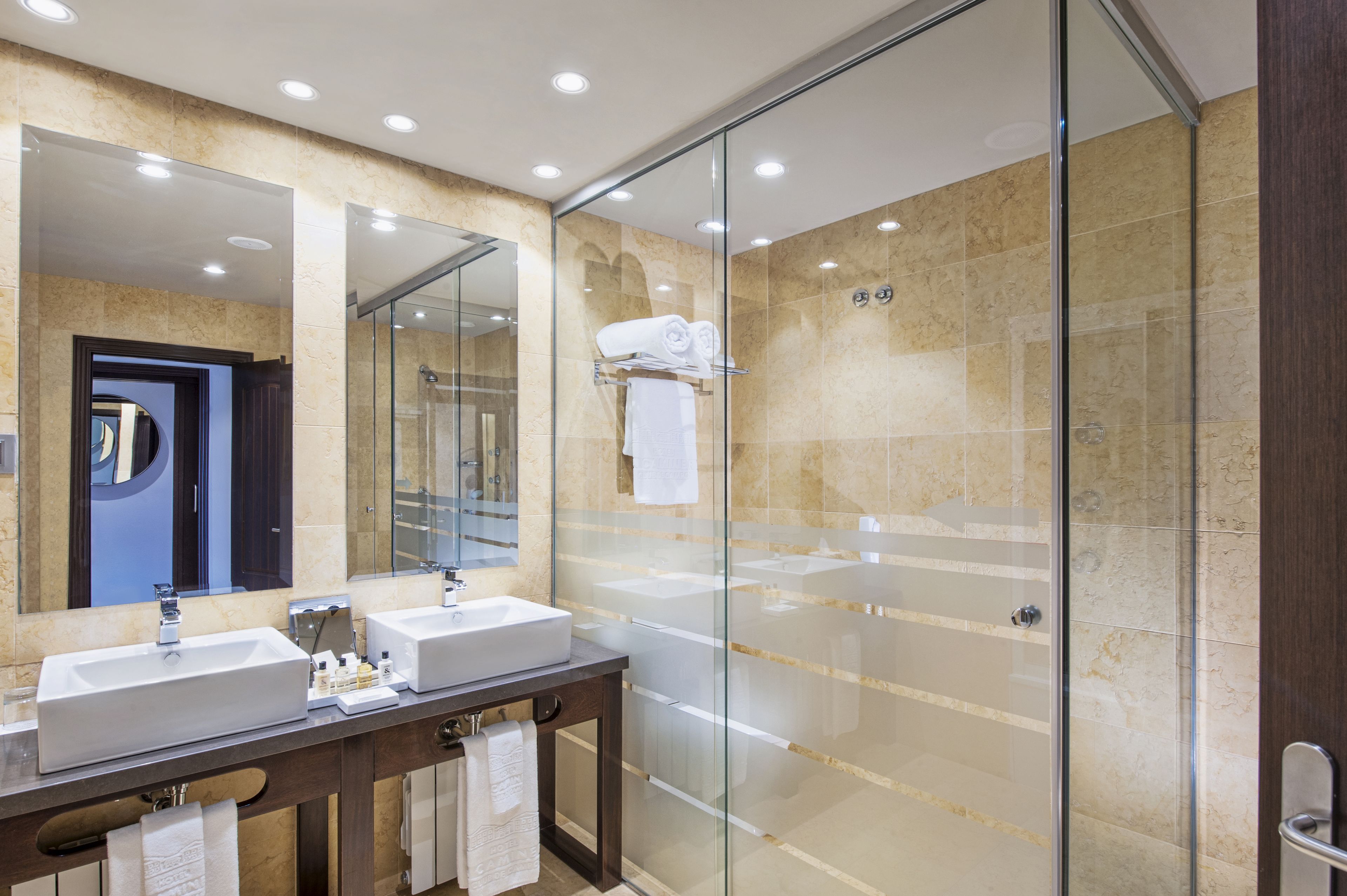 Un baño moderno con cabina de ducha de vidrio, tocador doble y un espejo grande.