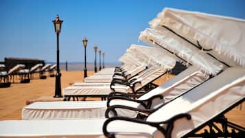 Una piscina al aire libre, sillones reclinables de piscina