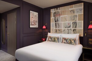 Una camera da letto con un letto grande, un telefono rosso e una parete decorata con quadri.