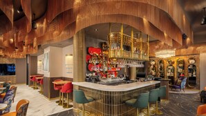 Eine Bar mit einer gebogenen Theke, mehreren Hockern und einer Auswahl an Flaschen und Gläsern.