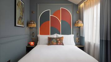 Een moderne hotelkamer met een groot bed, een decoratief hoofdbord, een klassieke telefoon en twee bedlampen.