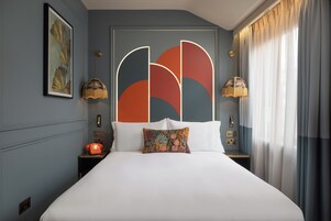 A modern hotel room with a large bed, a decorative headboard, a classic telephone, and two bedside lamps.