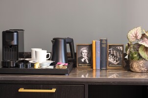 Angolo caffè con una macchina da caff è, tazze e un vassoio con snack. Sul bancone ci sono libri e una foto incorniciata.