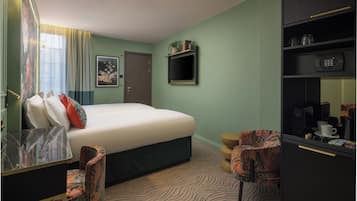Ein Hotelzimmer mit Bett, Schreibtisch, Stuhl, Kleiderschrank und einem kleinen Regal mit Pflanze und Dekoration.