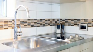 A modern kitchen with a stainless steel sink, a faucet, and a backsplash with a mosaic tile pattern.