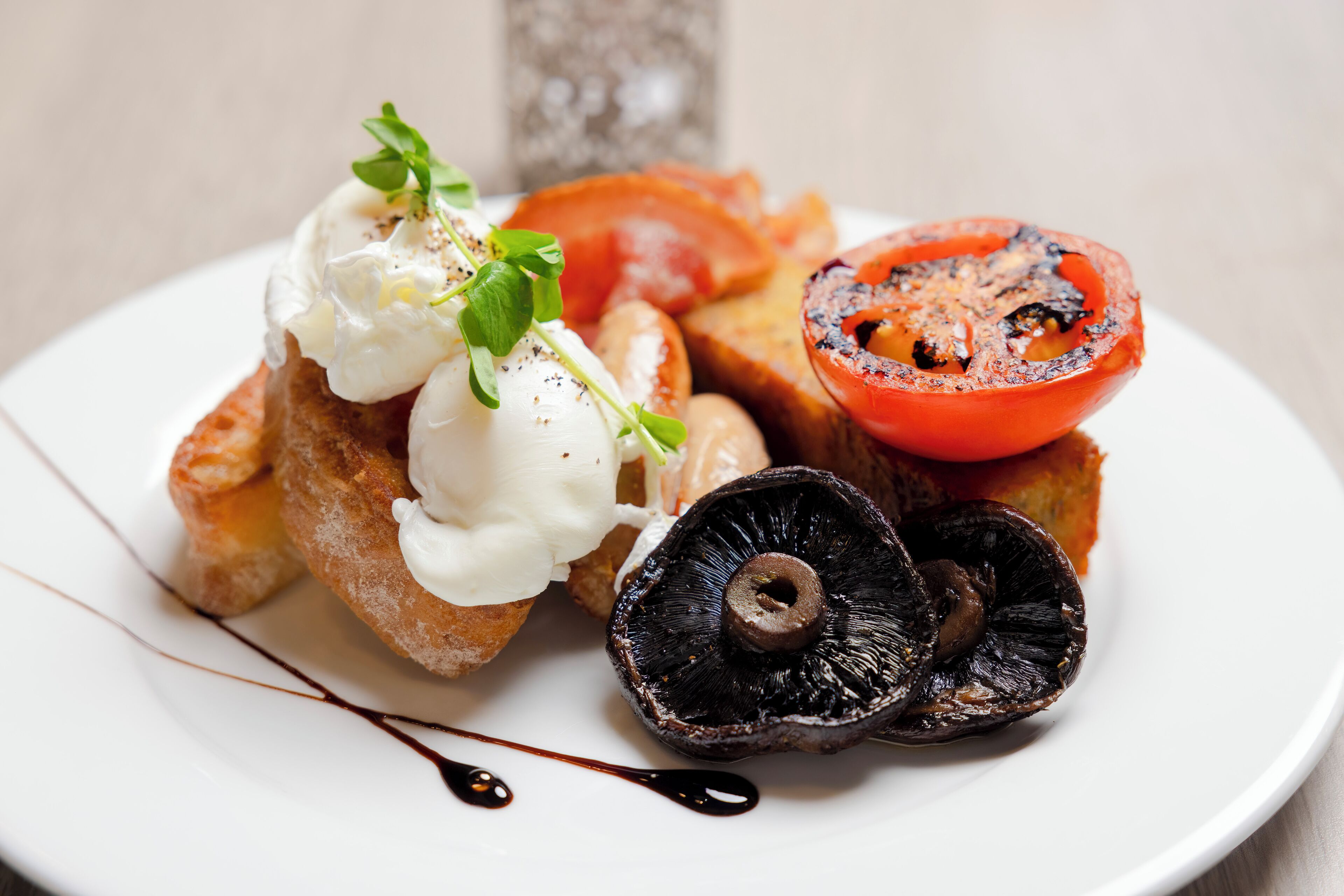 A plate with grilled tomato slices, a poached egg, and a mushroom.