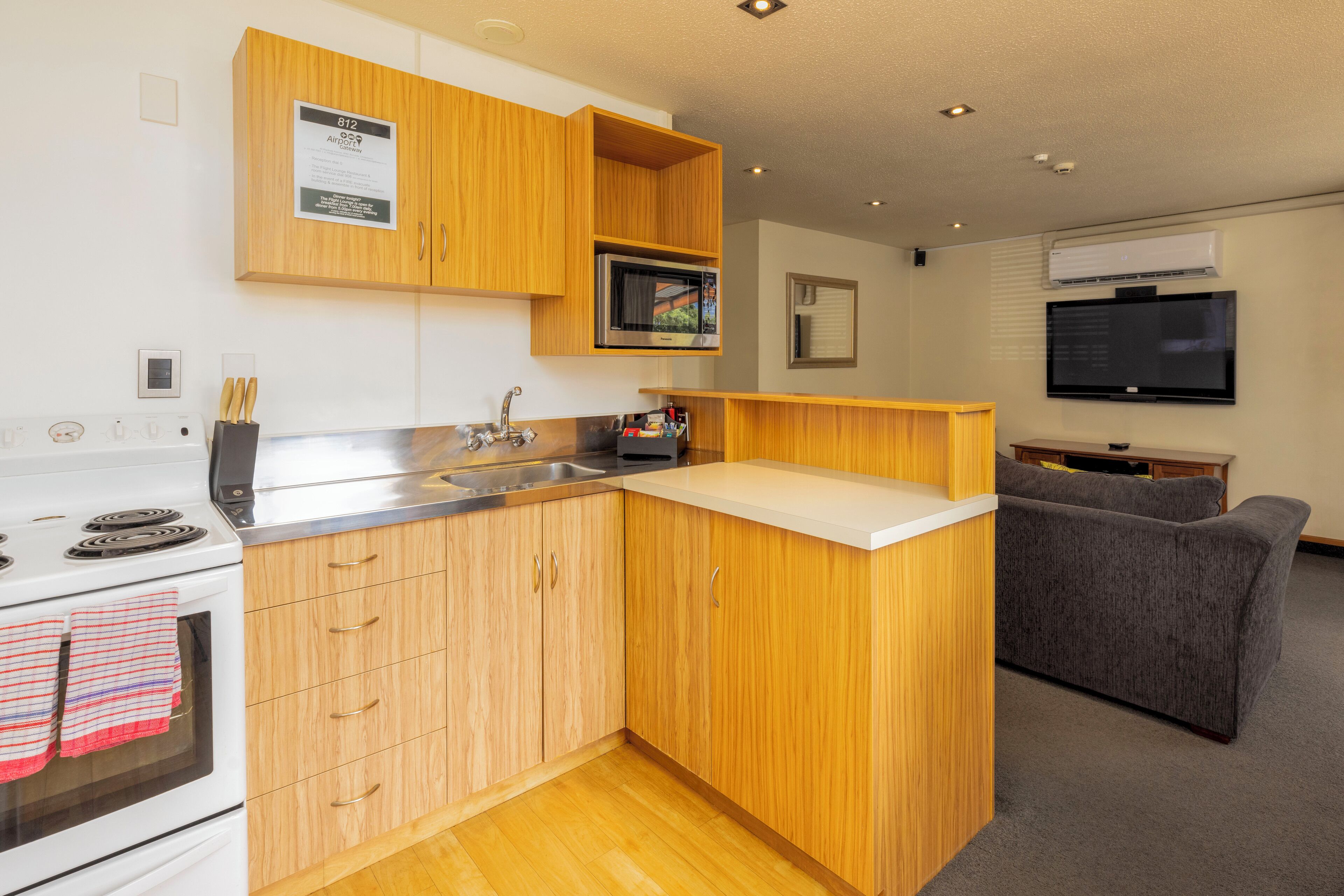 A compact kitchen with wooden cabinets, a microwave, and a built-in oven.