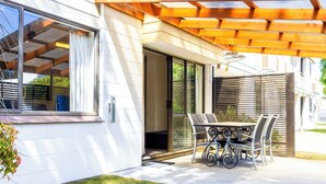A patio with a table and chairs, a sliding glass door, and a wooden pergola.
