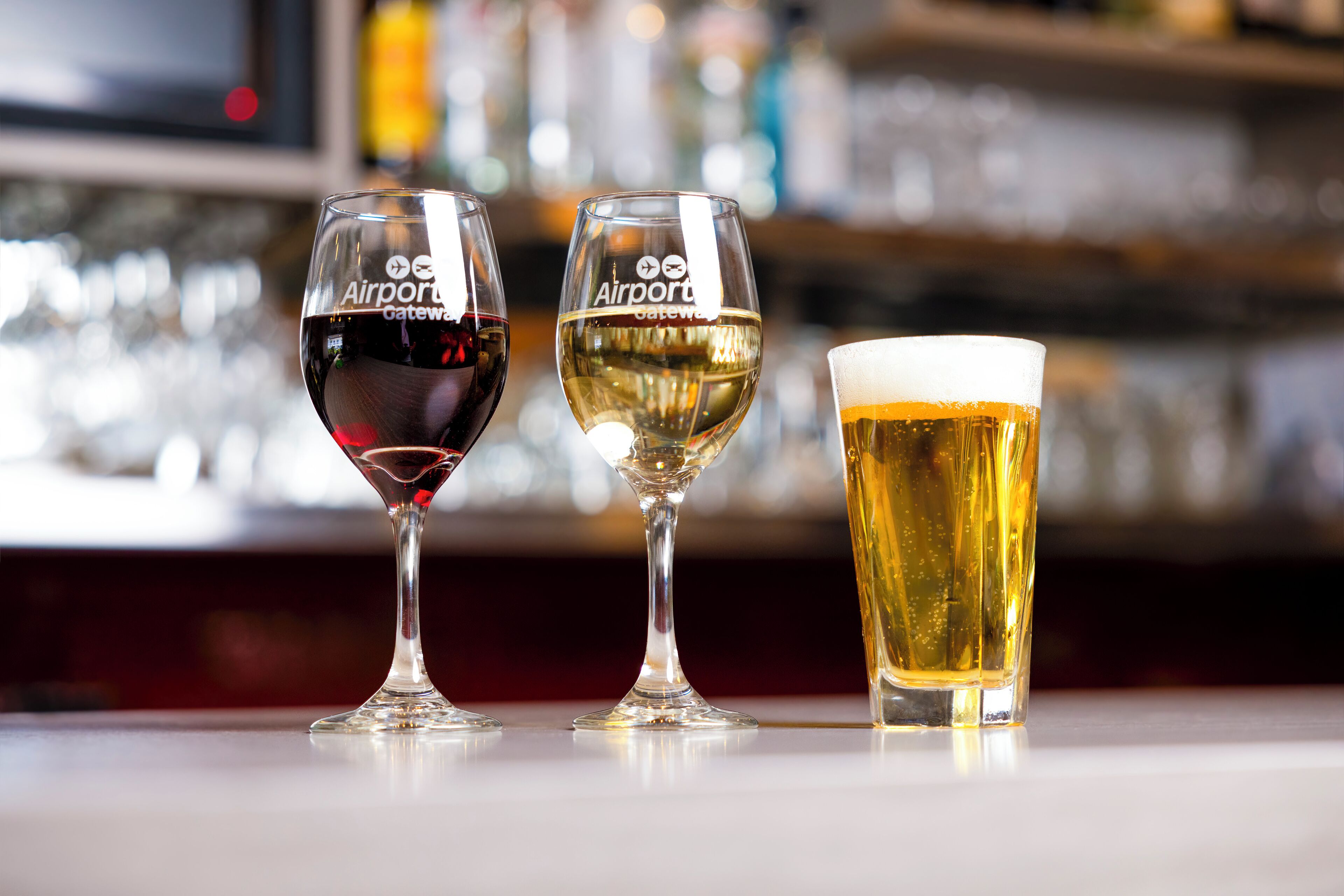 Three glasses of different beverages on a bar counter.