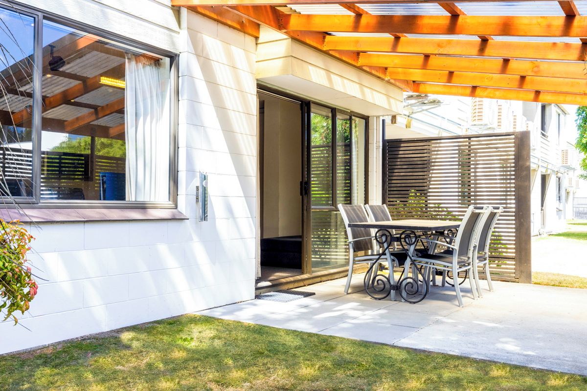 A modern house with a patio, a sliding glass door, and a wooden pergola.