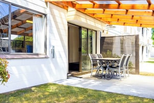 A modern house with a patio, a sliding glass door, and a wooden pergola.