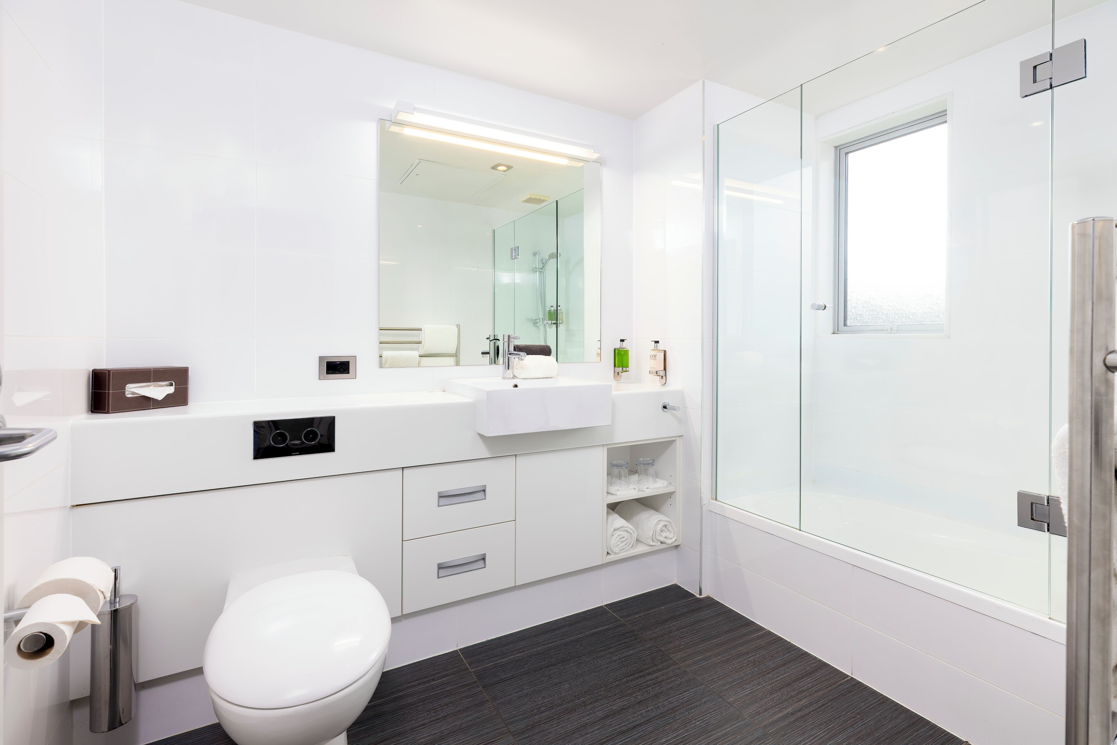 Een moderne badkamer met toilet, wastafel en douche.