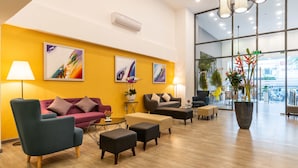 Un hall d’entrée moderne avec un mur d’accent jaune, un mobilier contemporain et de grandes fenêtres offrant une vue sur la ville.