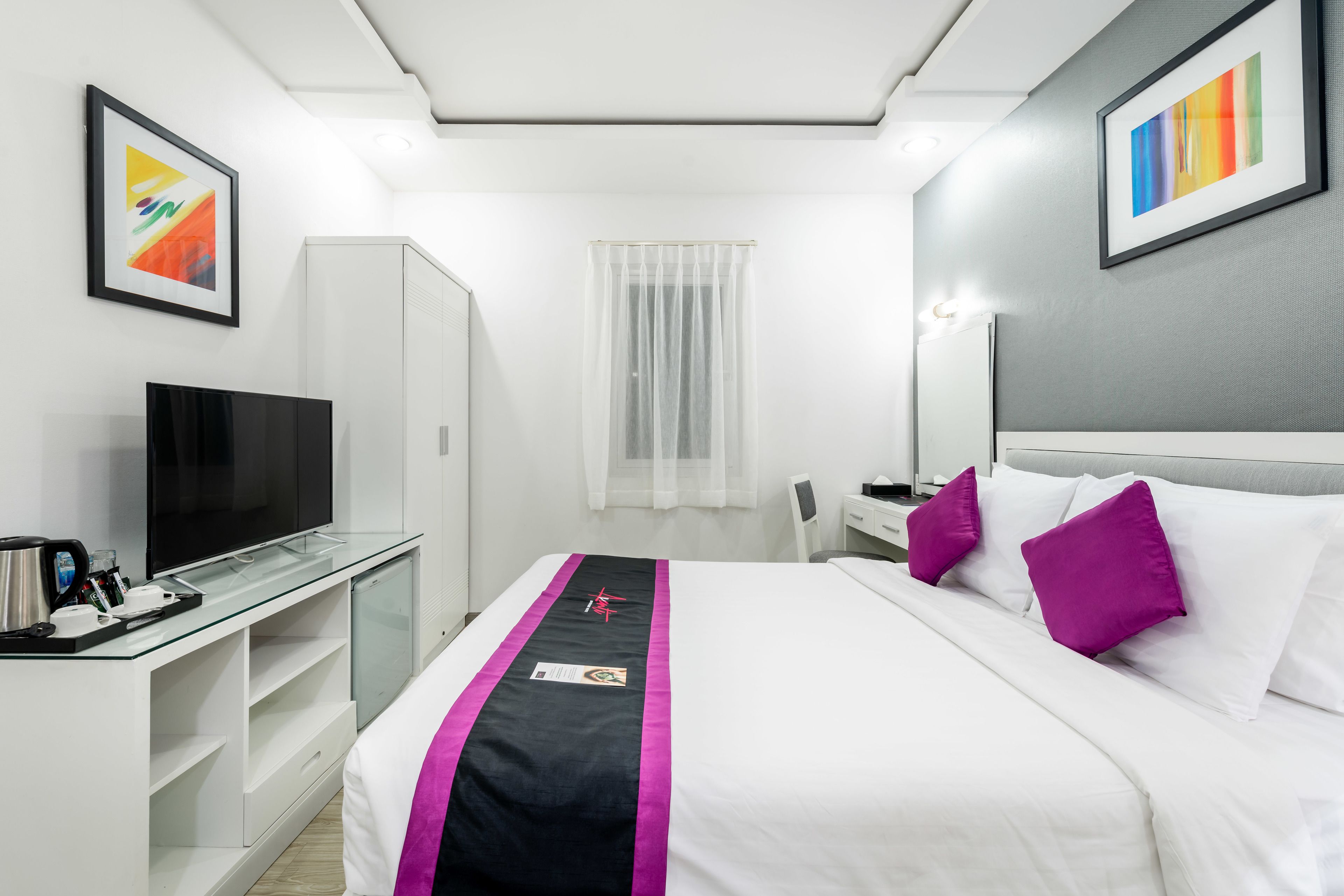 Una habitación de hotel con cama, televisión, escritorio y armario.