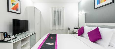 A hotel room with a bed, a TV, a desk, and a wardrobe.