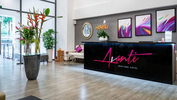 Un espace d’accueil moderne, avec un comptoir en verre, des plantes en pot et des œuvres d’art abstraites accrochées au mur.