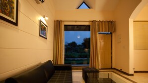 Hotelkamer met een bank, een glazen tafel, uitzicht op de maan en een deur naar buiten.