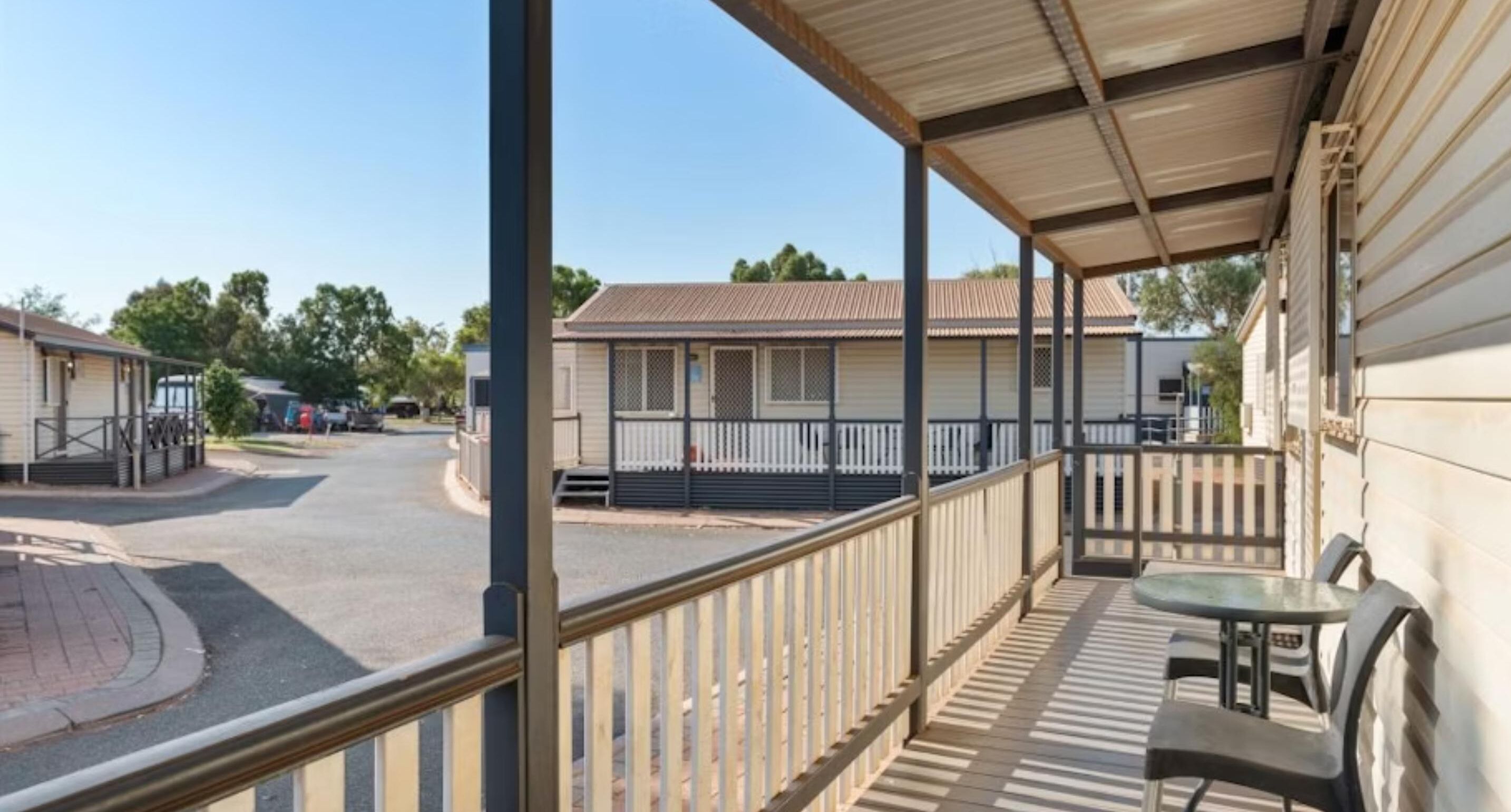 A covered outdoor area with a table and chairs, a view of a street with buildings, and a fenced area.