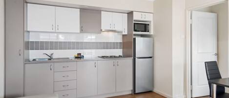 Una cocina moderna con armarios blancos, un microondas, un refrigerador y un lavabo.