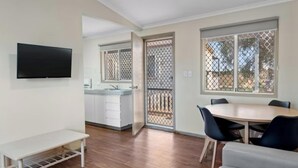 Una cocina moderna con armarios blancos, un lavabo y un ventanal con mosquitera.