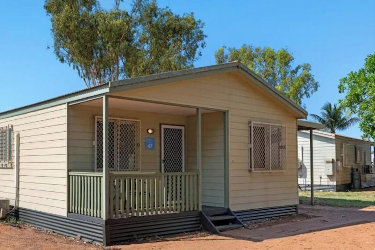 Ein Bungalow mit Veranda, einem kleinen umzäunten Bereich und einem Hinweisschild für Einheit 47.