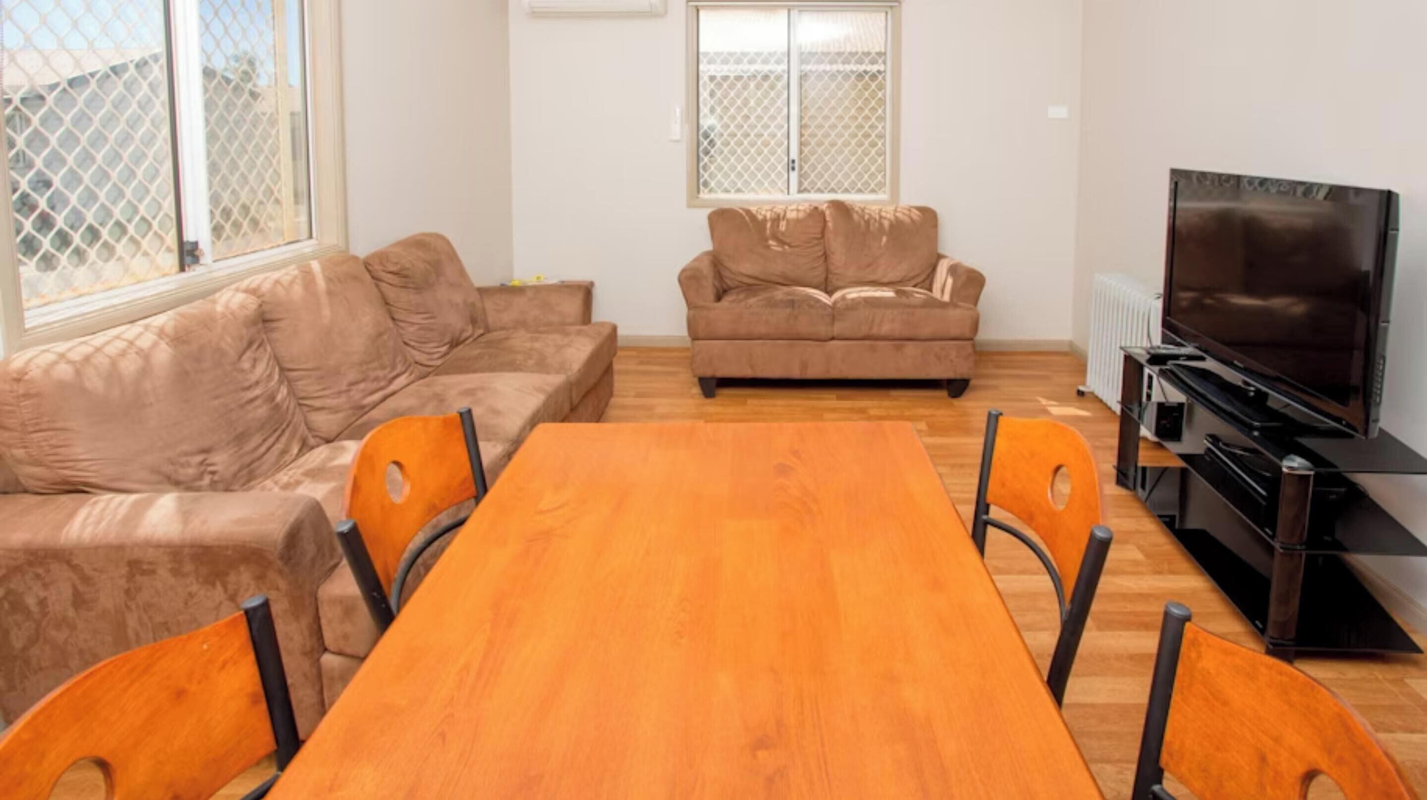 A living room with a wooden dining table, two sofas, and a television.